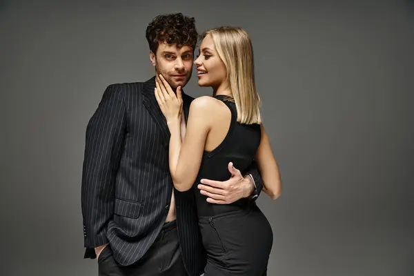 Homem bonito em traje de designer vermelho posando com modelo loira em fundo vibrante, casal na moda — Fotografia de Stock