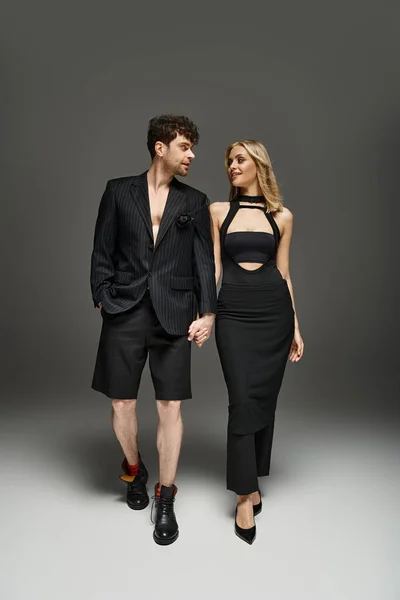 Handsome man in red designer attire posing with blonde model on vibrant background, trendy couple — Stock Photo