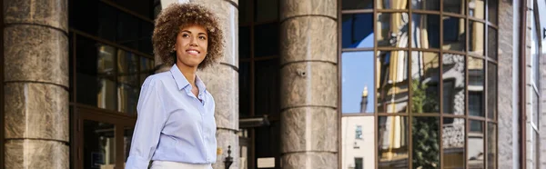 Feliz mulher afro-americana sorrindo e de pé em frente ao hotel, bandeira horizontal — Fotografia de Stock