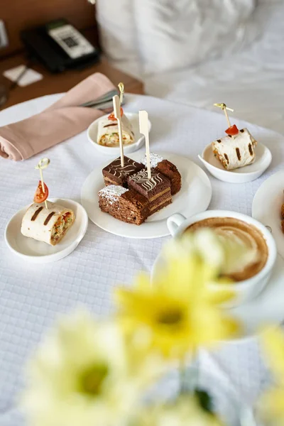 Service de chambre d'hôtel avec cappuccino frais et une variété de petits déjeuners, croissants et fruits — Photo de stock