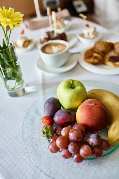 Hotel room service with fresh cappuccino and a variety of breakfast food, fresh flowers and fruits — Stock Photo