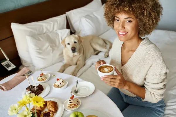 Glücklich afrikanisch-amerikanische Frau genießt Service in der Nähe von Labrador-Hund in haustierfreundlichen Hotelzimmer — Stockfoto