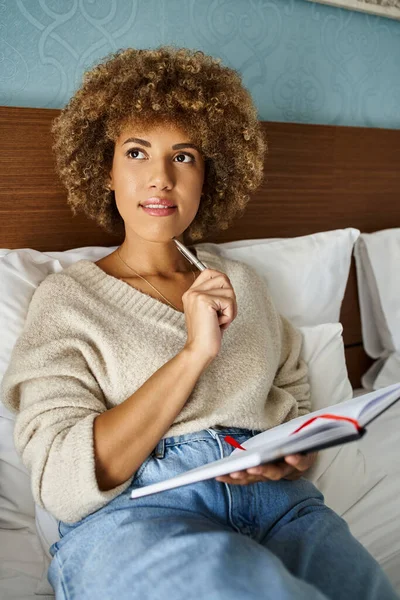 Femme afro-américaine aux cheveux bouclés et coûteuse planifiant son prochain voyage dans un carnet — Photo de stock