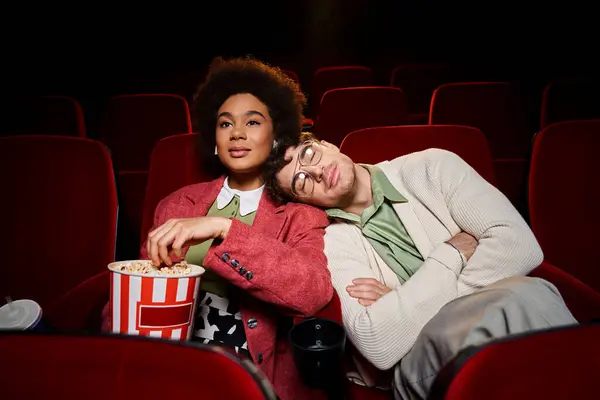 Hombre guapo disfrutando de una cita en el cine con su novia afroamericana con la cabeza en el hombro - foto de stock