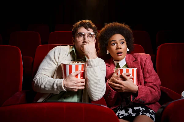 Astonished shocked diverse couple in retro stylish attires watching movie at cinema, Valentines day — Stock Photo