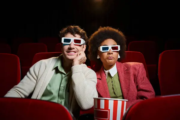 Веселая мультикультурная молодая пара в ретро 3D очках, прекрасно проводящая время в кино на свидании — стоковое фото