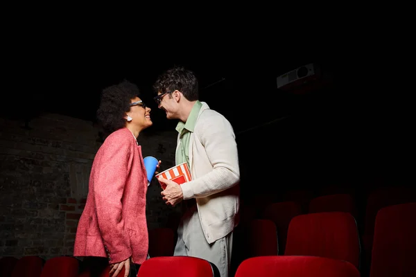 Jolly young multiracial couple smiling happily at each other while on date at cinema, Valentines day — Stock Photo