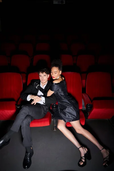 Appealing good looking diverse couple hugging on red cinema chairs on date on Valentines day — Stock Photo