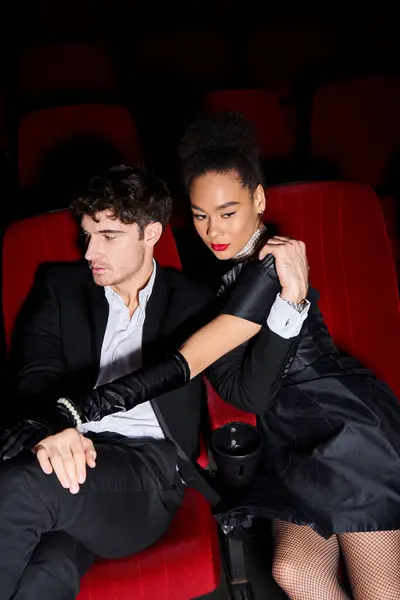 Attraente giovane coppia multiculturale in posa insieme su sedie cinema rosso in data il giorno di San Valentino — Foto stock