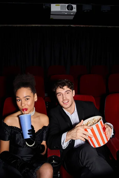 Jolly african american woman drinking while her handsome boyfriend holding popcorn at cinema — Stock Photo