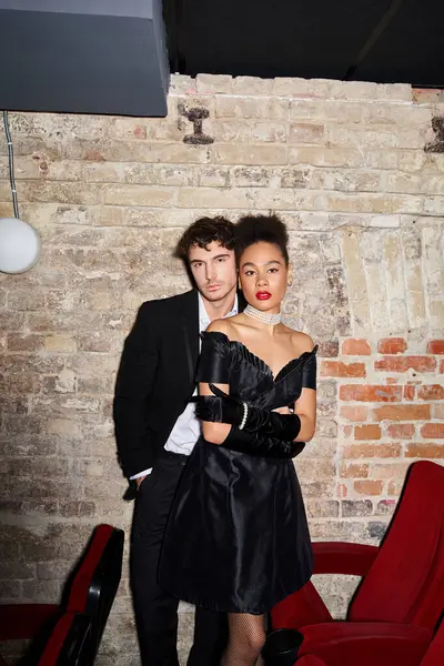 Attraktives multiethnisches Paar in Abendkleidern posiert zusammen und schaut beim Date in die Kamera — Stockfoto