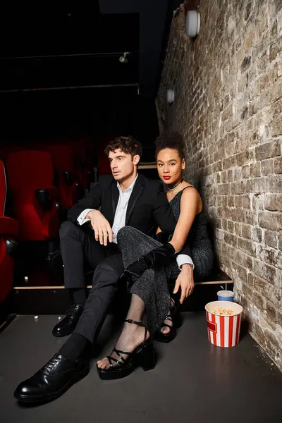 Attractive multiracial couple in black elegant attires sitting at cinema on date on Valentines day — Stock Photo