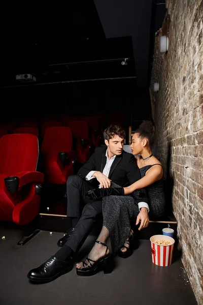 Séduisant couple multiethnique dans des tenues élégantes passer du temps ensemble au cinéma, Saint Valentin — Photo de stock