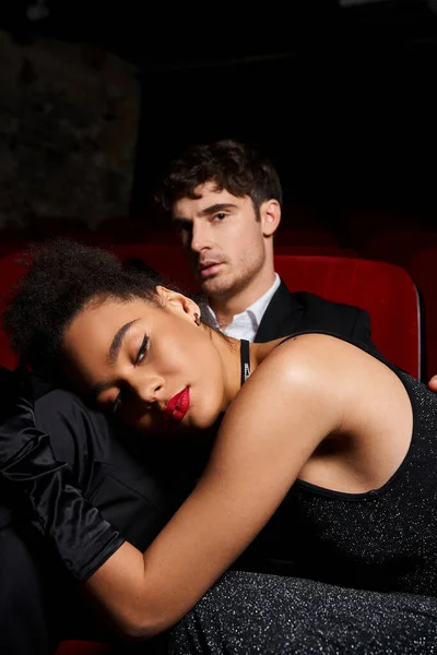 Appealing young multiracial couple in black elegant outfits posing at cinema, Valentines day — Stock Photo