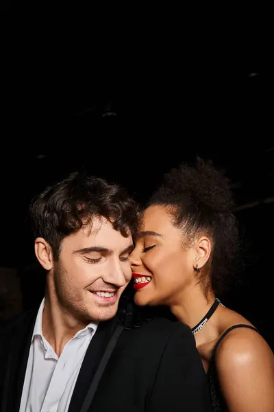 Pareja alegre multicultural en traje de noche posando amorosamente y sonriendo felizmente, el día de San Valentín — Stock Photo