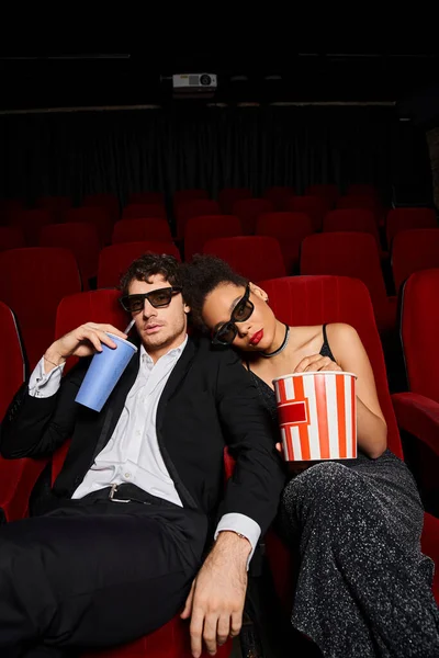 Atractivo joven pareja diversa con gafas 3d viendo película con palomitas de maíz y refrescos, Día de San Valentín - foto de stock