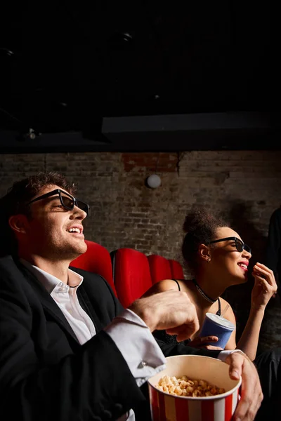 Buena pareja alegre y diversa con gafas 3d viendo la película en la fecha, día de San Valentín - foto de stock