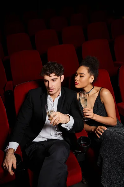 Belo casal multicultural em trajes elegantes sentado com champanhe nas mãos no dia dos namorados — Fotografia de Stock