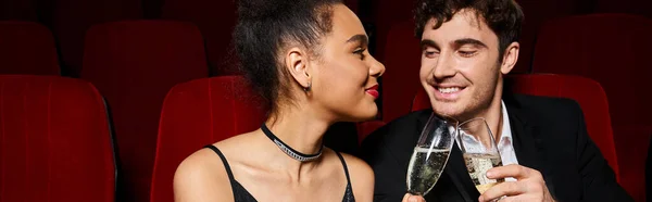 Multiracial couple in elegant outfits clinking champagne glasses and looking at each other, banner — Stock Photo