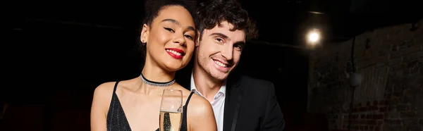 Jolly multiracial couple in elegant outfits with champagne in hands smiling at camera, banner — Stock Photo