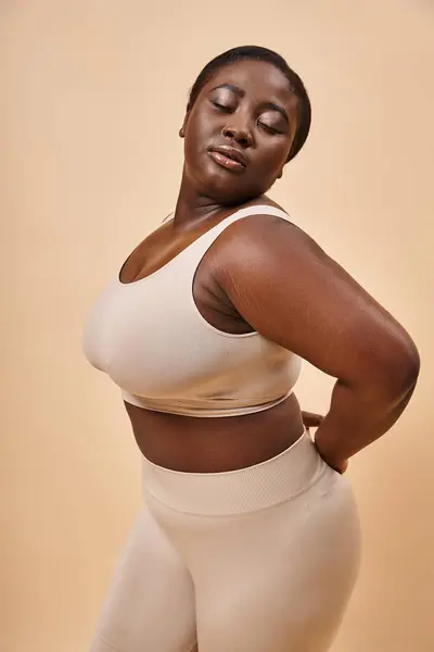 Young plus size african american woman in underwear posing on beige background, body positive — Stock Photo