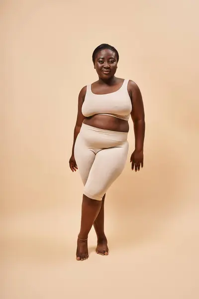 Plus size modello afroamericano in abito beige posa su uno sfondo di corrispondenza, corpo positivo — Foto stock