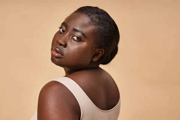 Young plus size african american woman in beige underwear posing against matching background — Stock Photo