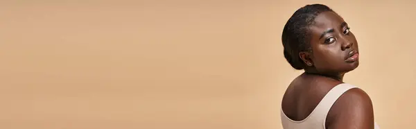 Giovane plus size donna africana americana in biancheria intima beige posa sullo sfondo corrispondente, banner — Foto stock