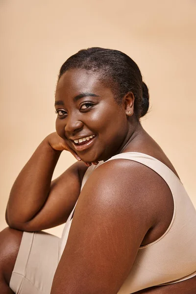 Plus size afrikanisch amerikanische Frau lacht und posiert vor beigem Hintergrund, Körper positiv — Stockfoto