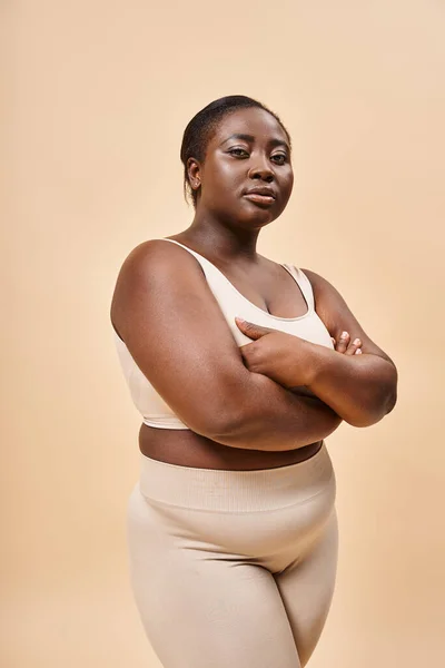 Happy plus size woman in beige underwear posing with crossed arms, body positive and self esteem — Stock Photo