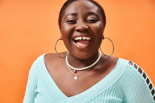 Porträt einer fröhlichen afrikanisch-amerikanischen Frau in blauem Langarm, die auf Orange lacht — Stockfoto