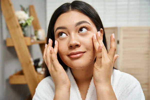 Concept de soins de la peau, jeune femme asiatique en peignoir de bain appliquer crème hydratante sur le visage et la recherche vers le haut — Photo de stock