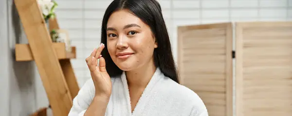Happy asian woman with acne applying cream on face and smiling while looking at camera, banner — Stock Photo