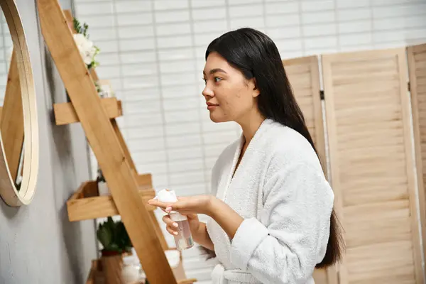 Young asian woman with brunette hair preparing to use facial cleansing foam in modern bathroom — Stock Photo