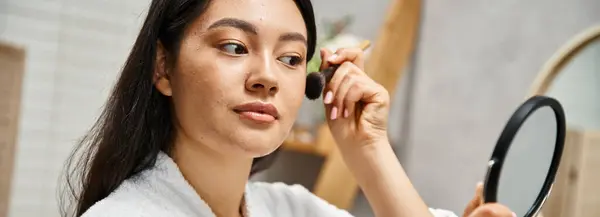 Mujer asiática joven con pelo morena aplicando maquillaje sobre la piel propensa al acné con cepillo, pancarta - foto de stock