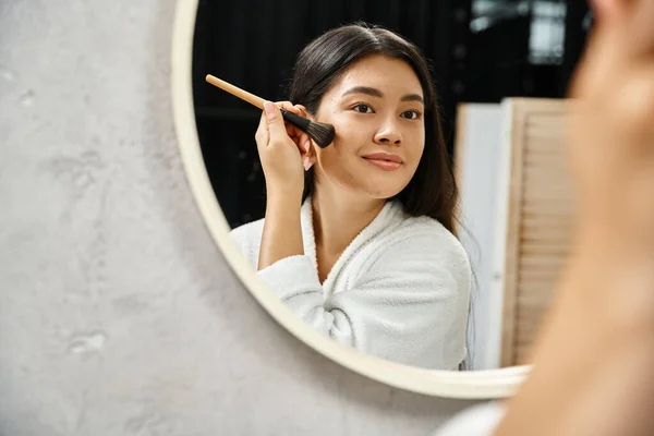 Brunette young asian woman applying face powder over acne-prone skin with brush at looking at mirror — Stock Photo