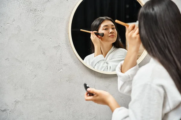 Jeune femme asiatique avec des cheveux bruns et l'acné application de poudre visage, problèmes de peau et de maquillage — Photo de stock
