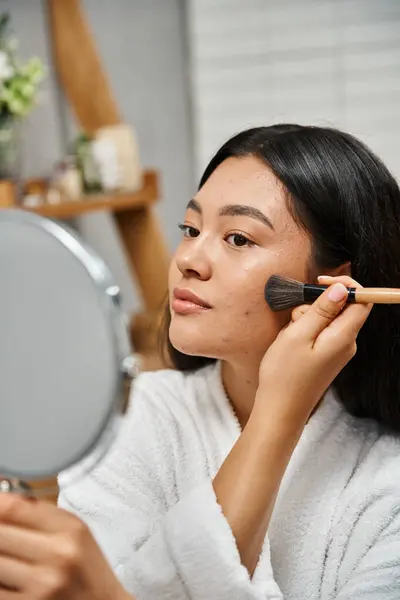 Jeune femme asiatique avec des cheveux bruns et l'acné sur la peau en appliquant de la poudre visage, problèmes de peau et de maquillage — Photo de stock