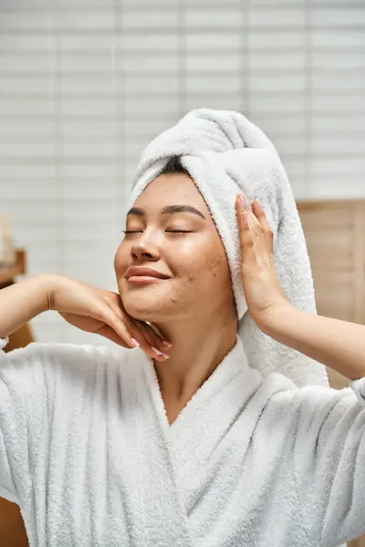 Plan vertical de heureux jeune femme asiatique avec la peau sujette à l'acné avec serviette blanche sur la tête dans la salle de bain — Photo de stock