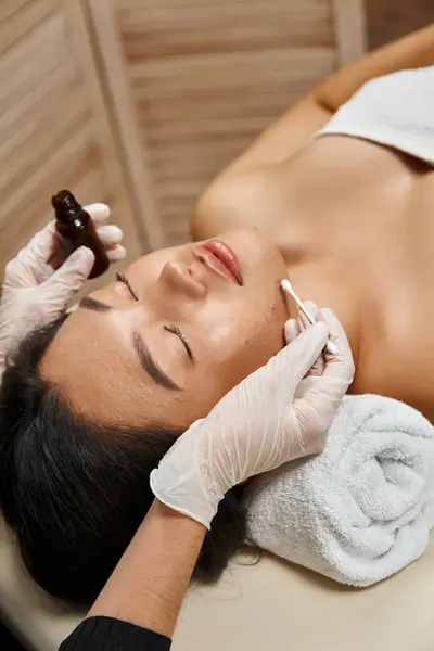 Soin de la peau, thérapeute appliquant le sérum de traitement avec coton-tige sur la femme asiatique à la peau sujette à l'acné — Photo de stock