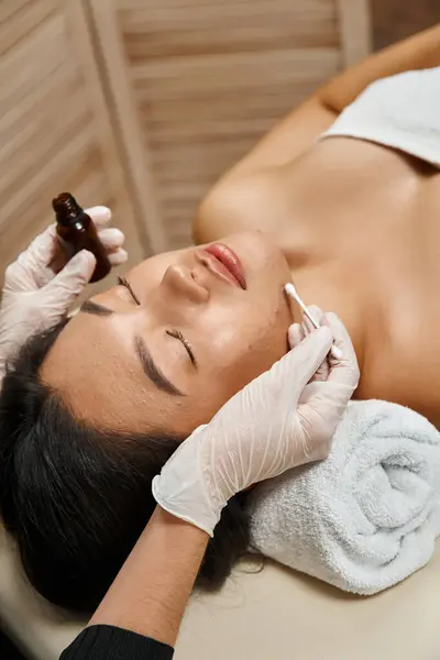 Skin care, therapist applying treatment serum with cotton swab on asian woman with acne-prone skin — Stock Photo