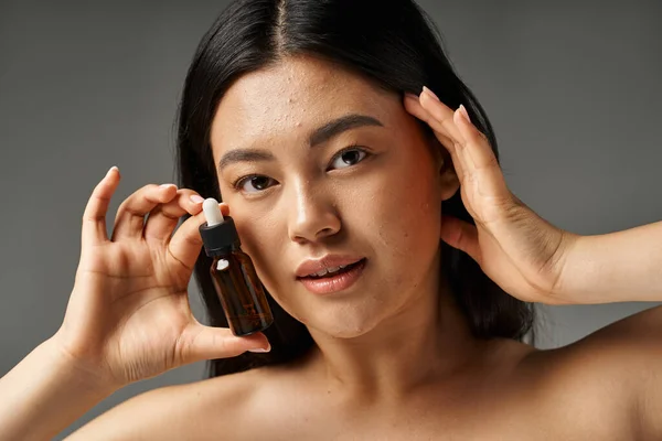 Jeune femme asiatique avec des cheveux bruns et l'acné peau sujette à regarder miroir dans la salle de bain, bannière — Photo de stock