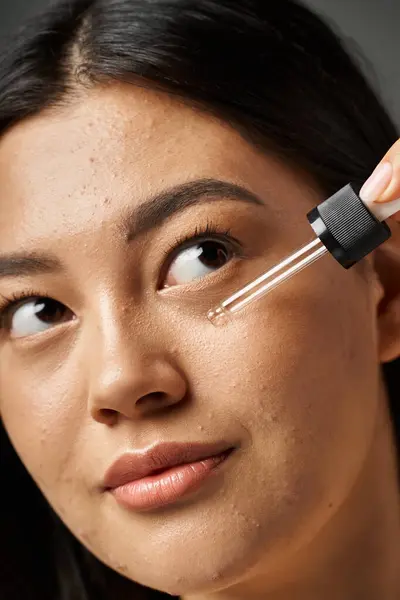 Young asian woman with brunette hair and acne prone skin looking at mirror in bathroom, banner — Stock Photo