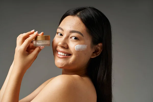 Mujer asiática joven con pelo morena y piel propensa al acné mirando el espejo en el baño, pancarta - foto de stock