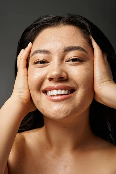 Young asian woman with brunette hair and acne prone skin looking at mirror in bathroom, banner — Stock Photo