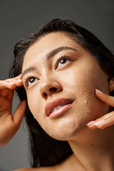 Молодая азиатка с брюнетками и прыщавой кожей, смотрящая на зеркало в ванной комнате, баннер — стоковое фото
