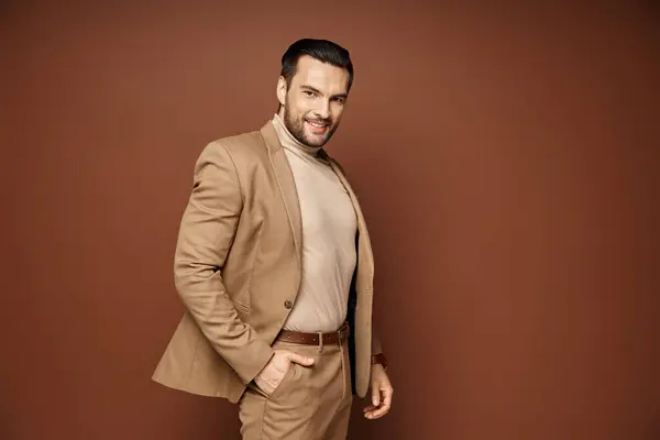 Cheerful man with bristle posing in stylish beige blazer with hand in pocket on beige backdrop — Stock Photo