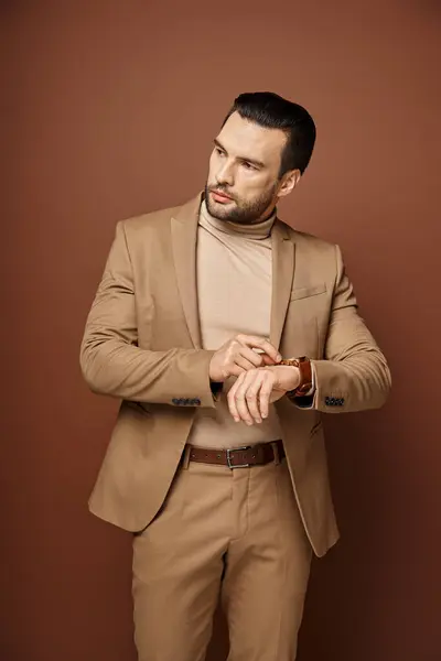 Handsome man in elegant attire checking his wristwatch on beige background, time management — Stock Photo