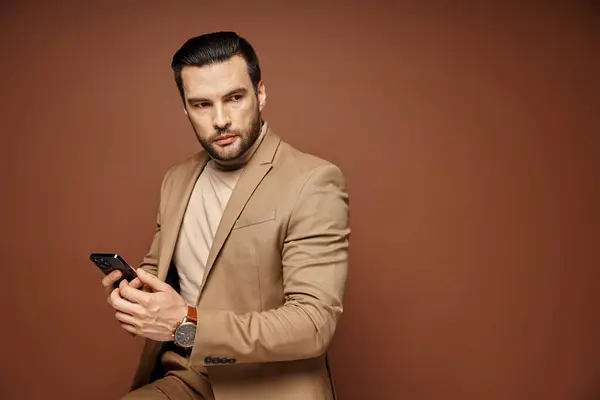 Handsome businessman in elegant attire checking smartphone on beige background, social media — Stock Photo