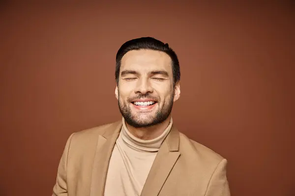 Porträt eines attraktiven Mannes in eleganter Kleidung, der mit geschlossenen Augen auf beigem Hintergrund lächelt — Stockfoto